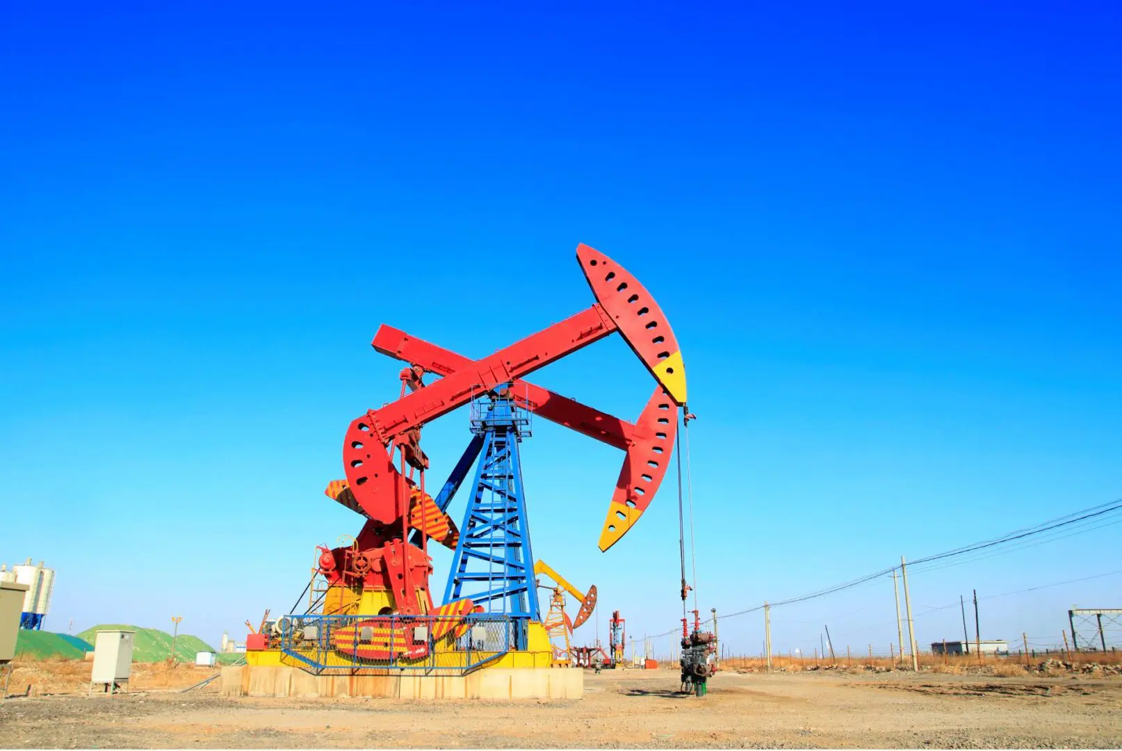 A red oil pumpjack extracting oil under a clear blue sky.